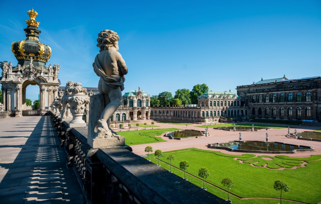 Blick von der Galerie auf die Orangenbäume im  Dresdner Zwinger mit Kronentor, Sandsteinfiguren, symmetrischem Rasen und Wasserbecken.