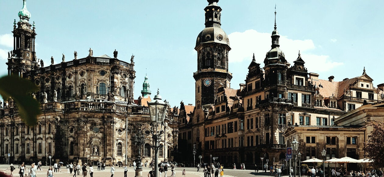 Residenzschloss Dresden und Hofkirche mit barocken Türmen, heller Sandsteinfassade und belebtem Theaterplatz.