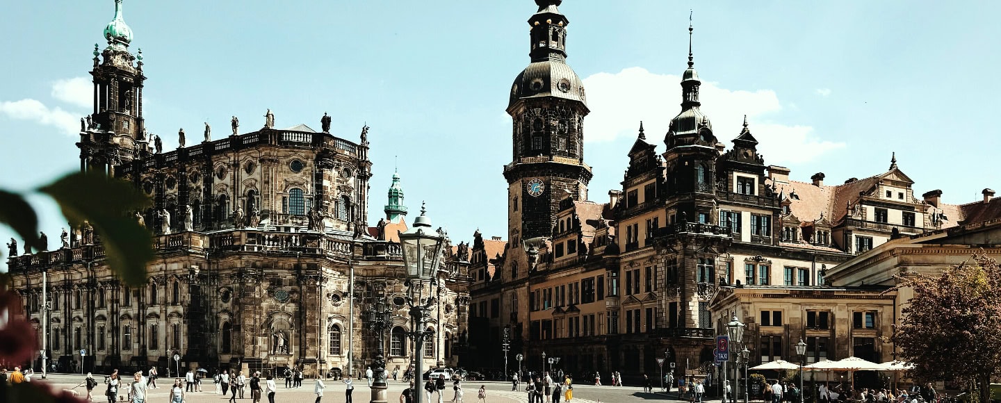 Residenzschloss Dresden und Hofkirche mit barocken Türmen, heller Sandsteinfassade und belebtem Theaterplatz.