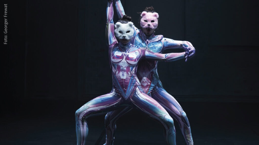Zwei Tänzer in farbigen Anzügen und Tiermasken performen auf Bühne
