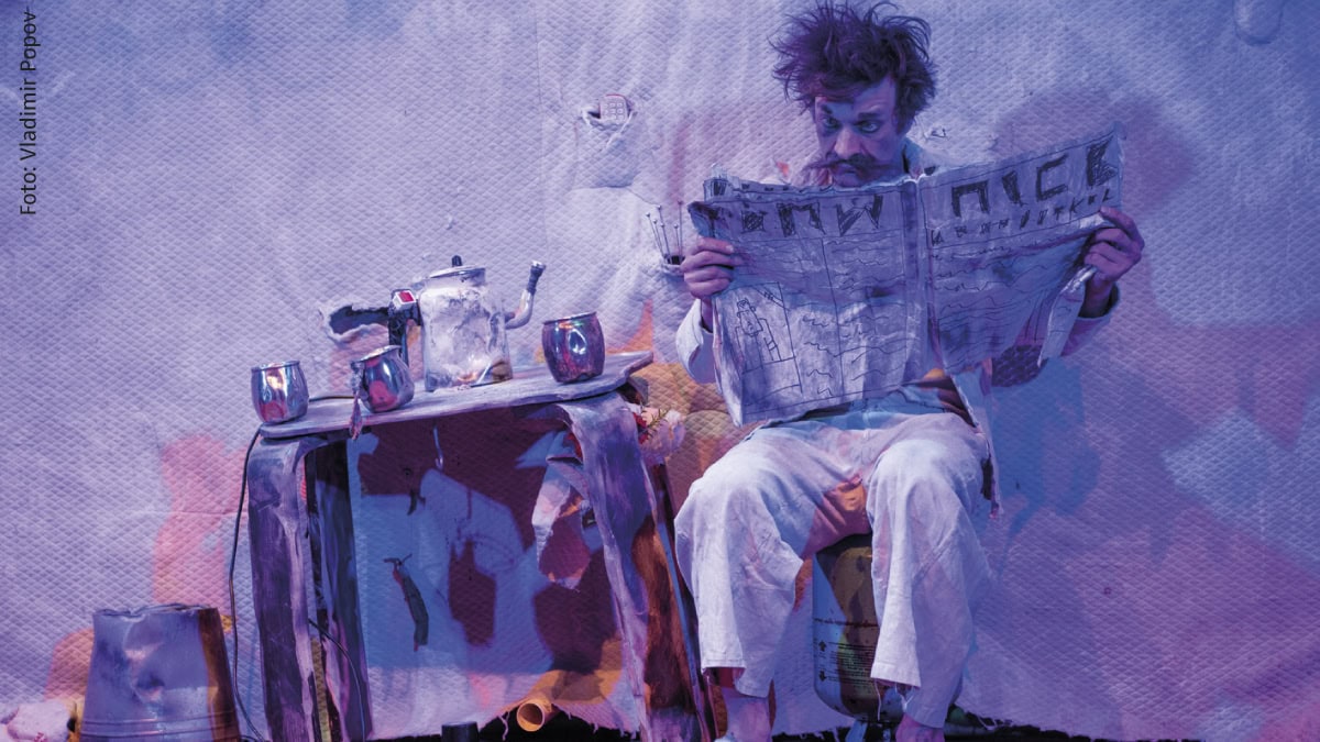 Mann mit wirrem Haar liest Zeitung an provisorischem Tisch