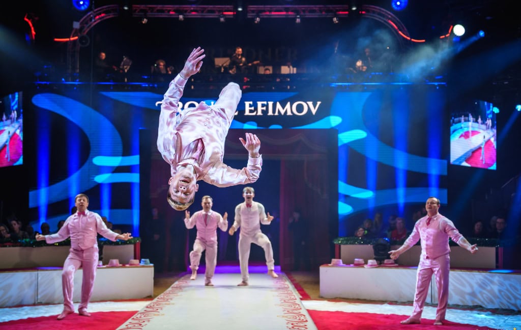 Zu sehen ist ein Zirkusauftritt einer Gruppe, wobei einer der Künstler gerade dabei ist, einen Salto zu machen. Der Auftritt fand im Rahmen des Dresdner Weihnachts-Circus 2024 statt.