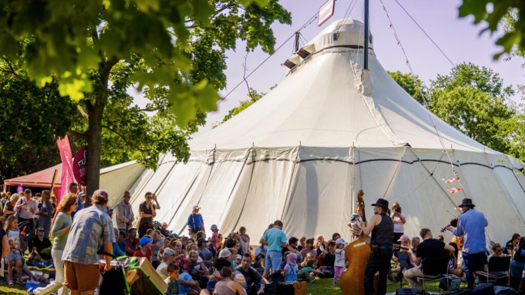 Zirkustheater-Festival Dresden 2026: Eine Menschenansammlung steht und sitzt vor einem Zirkuszelt.