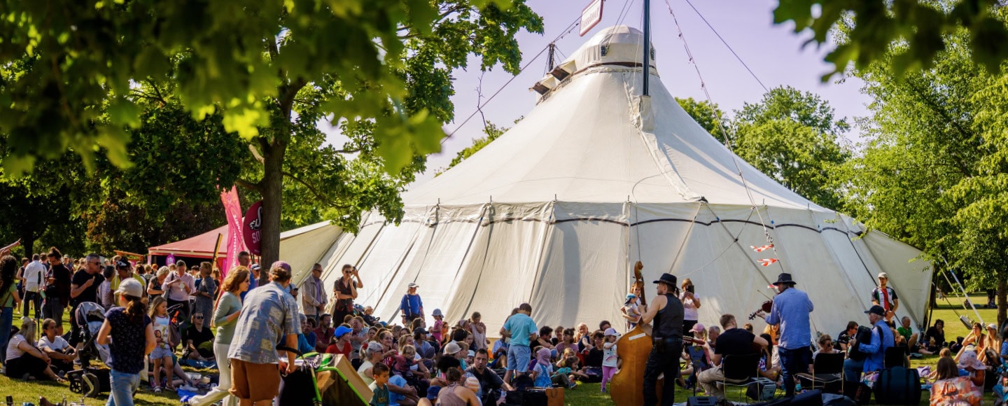 Zirkustheater-Festival Dresden 2026: Eine Menschenansammlung steht und sitzt vor einem Zirkuszelt.