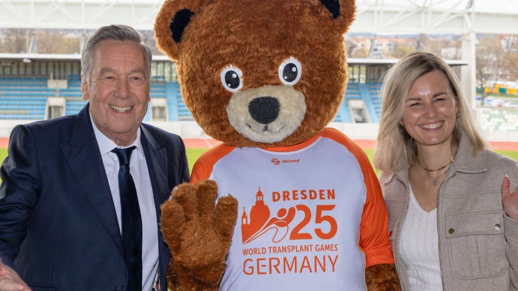 Schlagersänger Roland Kaiser und Tamara Schwab mit dme Maskottchen der Trasnplant Games im Stadion