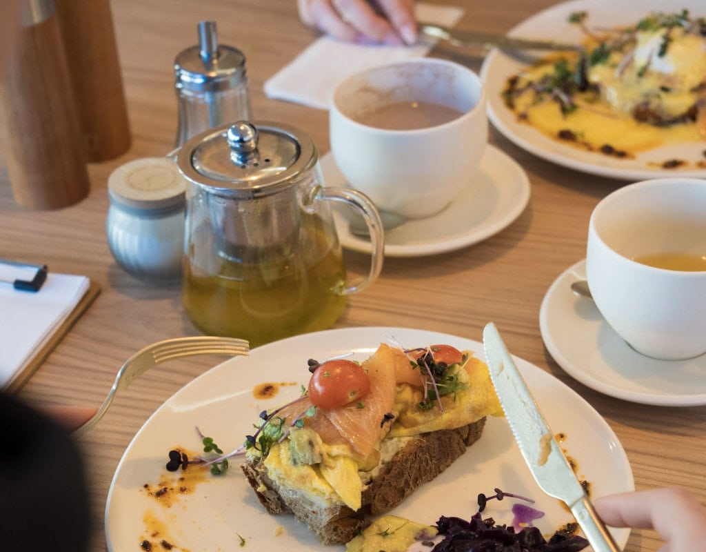 rühstück im Alma Daily Brunch in Dresden mit Omelett auf Brot, Lachs, Tee und Heißgetränken auf Holztisch