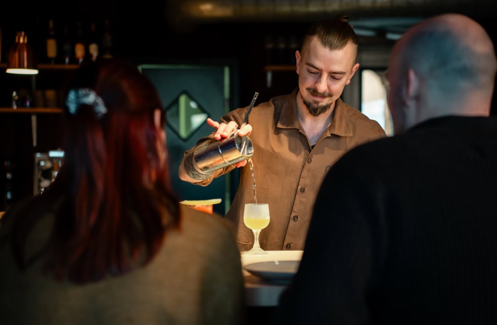 Ein Barkeeper der Cocktailbar nook in Dresden gießt einen Drink ein.