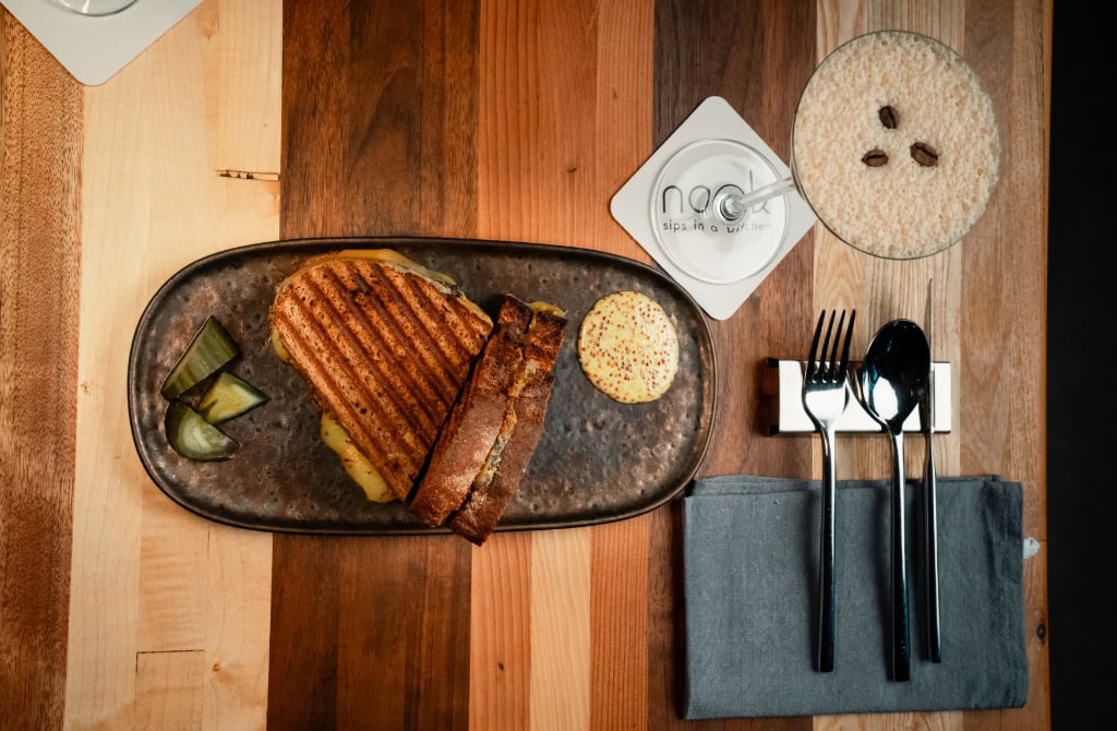 Zu sehen ist ein fein angerichtetes Sandwich, daneben ein Espresso Martini.