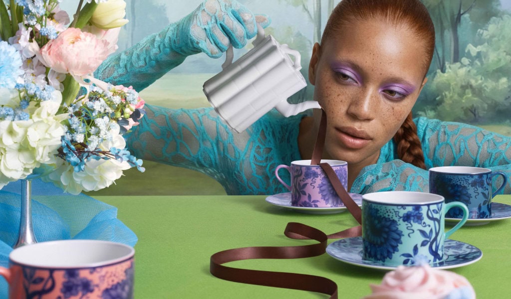 Gedeckter Tisch mit bunten Tassen und Kuchen, Person schenkt Tee ein, Porzellantassen der porzellanmanufaktur meissen