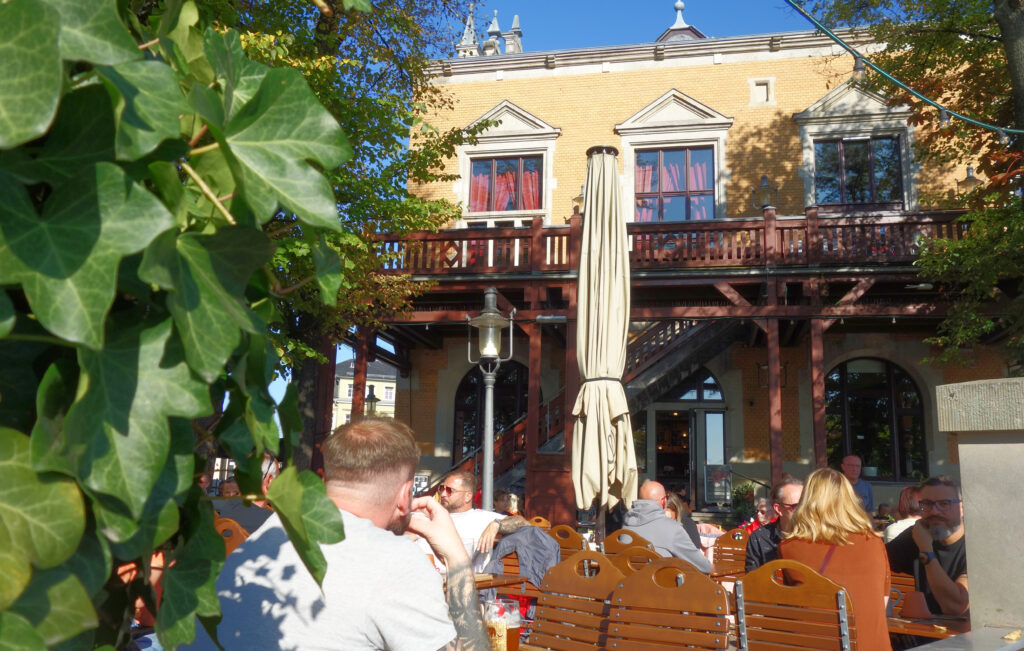 Blick in den Biergarten des Brauhaus Watzke mit Menschen, die am Tisch sitzen.