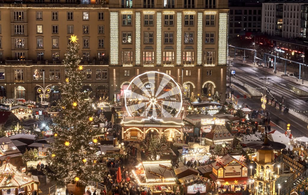 Eine Nahaufnahme des Striezelmarkts in Dresden: Zu sehen sind der große Weihnachtsbaum, das Riesenrad und viele Stände.