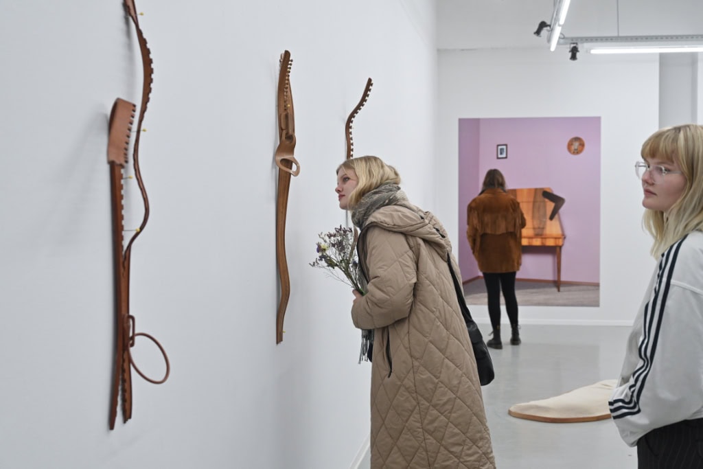 Zwei Frauen schauen sich an der Wand hängende Kunstwerke aus Holz in der Galerie im Kunstverein Dresden in Dresden-Neustadt.
