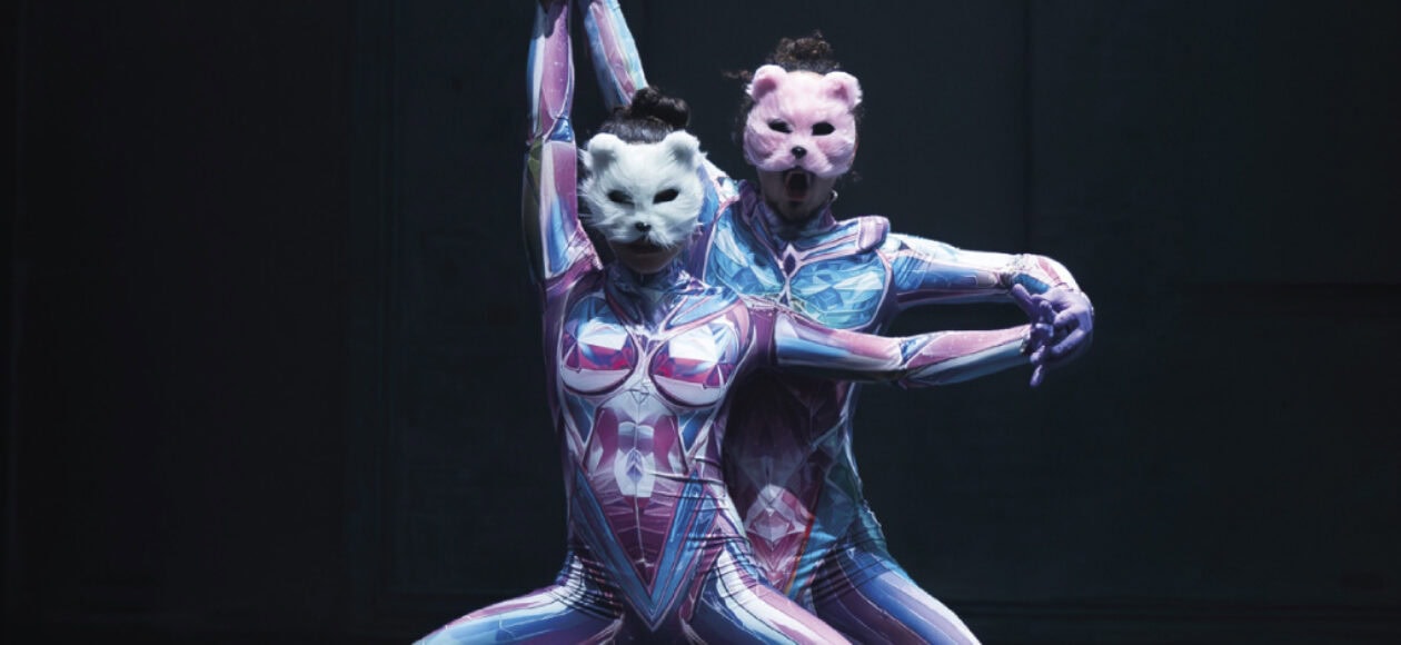 Zwei Tänzer in farbigen Anzügen und Tiermasken performen auf Bühne