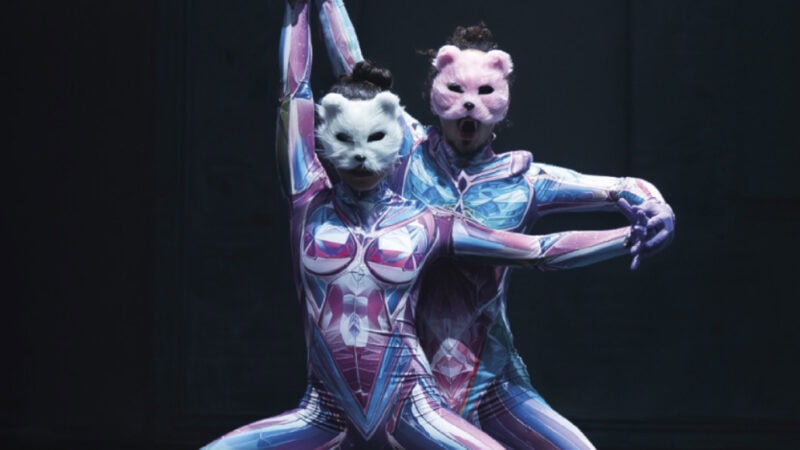 Zwei Tänzer in farbigen Anzügen und Tiermasken performen auf Bühne
