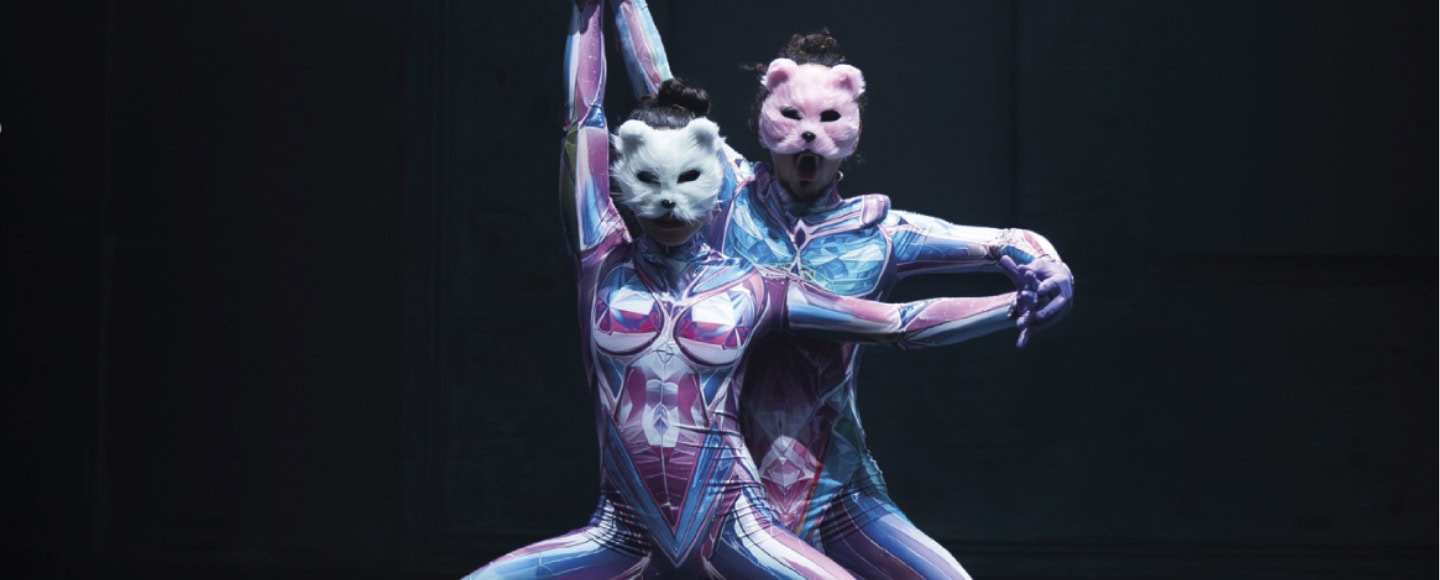 Zwei Tänzer in farbigen Anzügen und Tiermasken performen auf Bühne