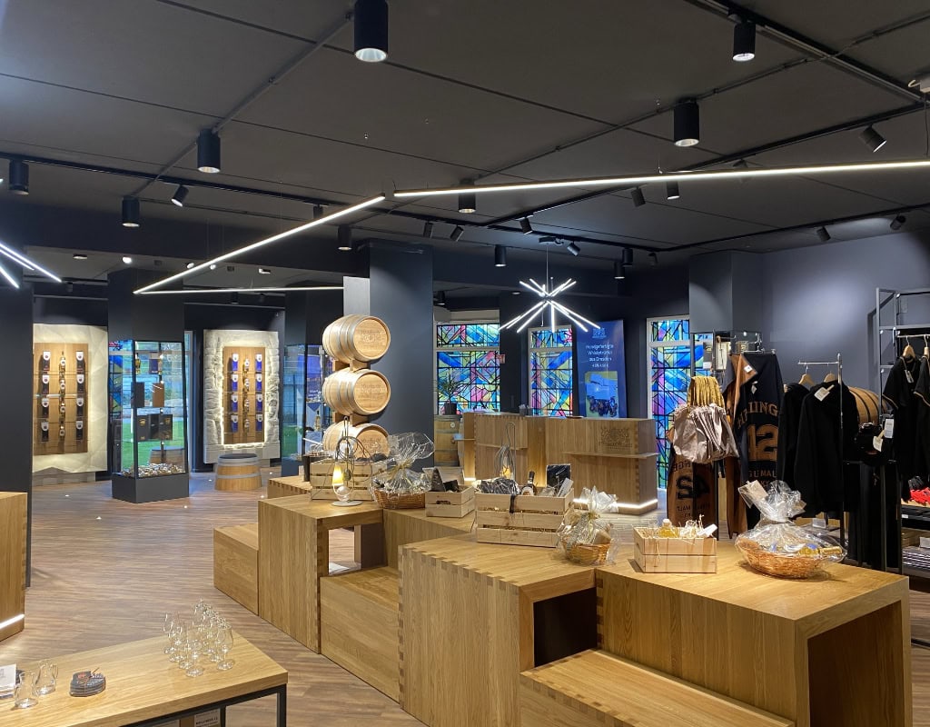 Das Besucherzentrum der Whisky Manufaktur Dresden von innen. Zu sehen sind Schaufenster mit Whiskyflaschen und Holzfässer.