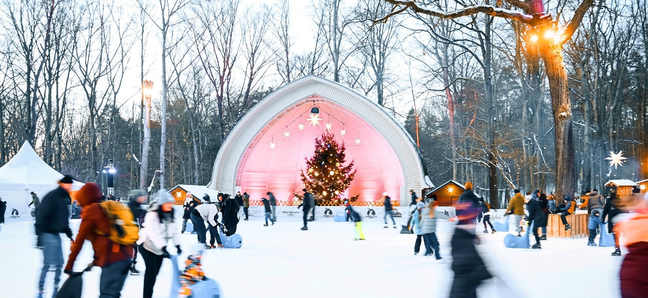 Eisläuferinnen und Eisläufer bewegen sich über die Eisfläche am Konzertplatz Weißer Hirsch in Dresden.