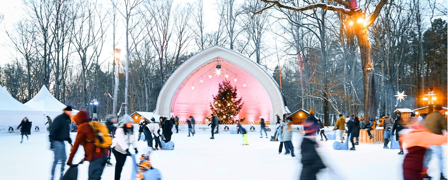 Eisläuferinnen und Eisläufer bewegen sich über die Eisfläche am Konzertplatz Weißer Hirsch in Dresden.