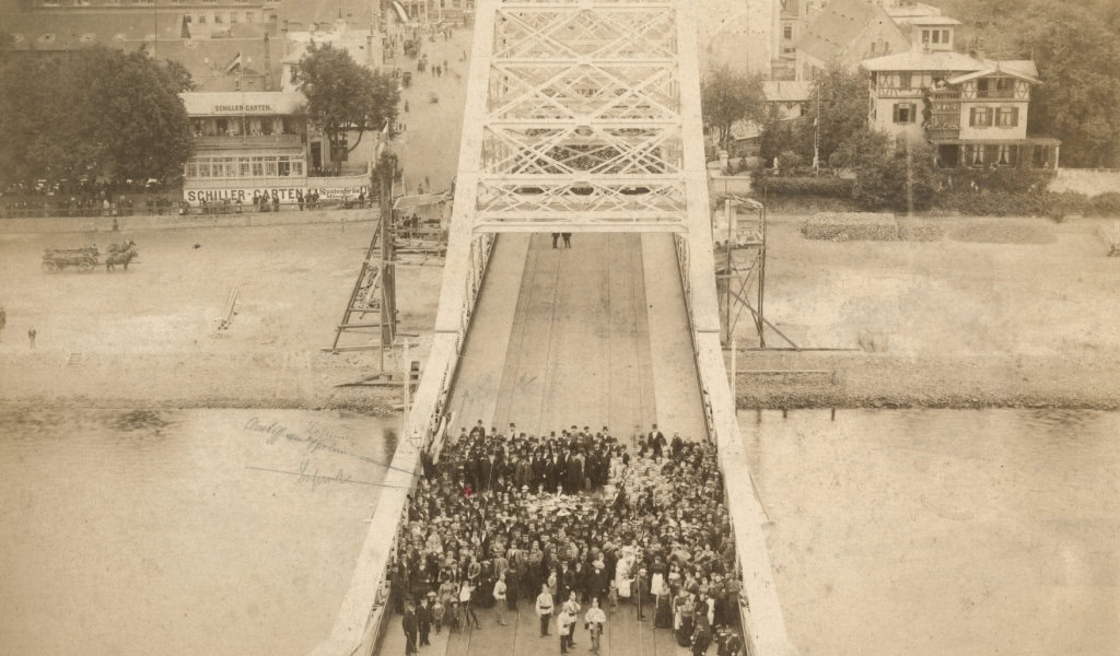 Sepiabild von Menschen auf der Brücke Blaues Wunder in Loschwitz, im Hintergund die Gaststätte Schillergarten