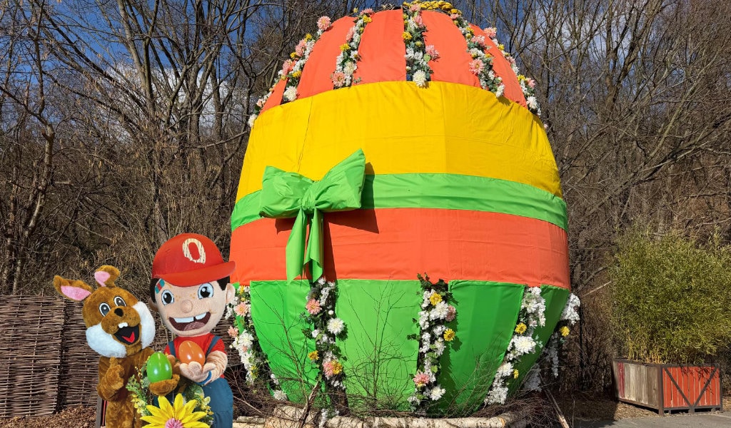 Ein riesiges verziertes Osterei mit Schleife steht in Freizeitpark. 