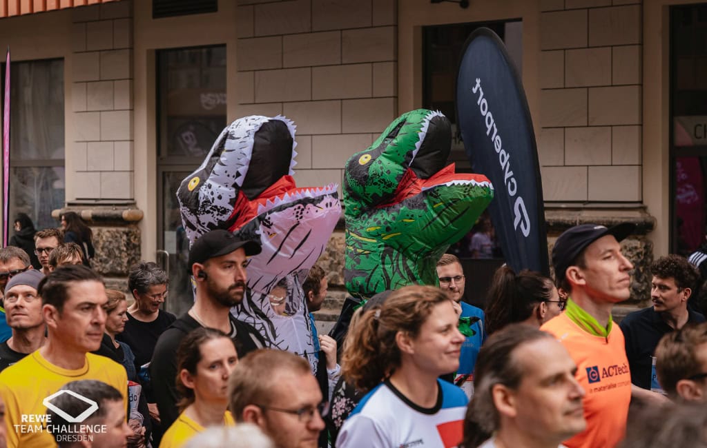 Bei der Rewe-Team-Challenge in Dresden geht es auch um den Spaß: Einige Gruppen absolvieren den Firmenlauf in amüsanten Kostümen, wie hier in Dino-Verkleidung.