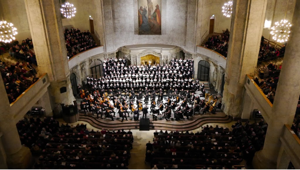 Kirchenraum der Kreuzkirche Dresden mit Chor, Orchester und dicht besetzten Emporen unter hohen Bögen.
