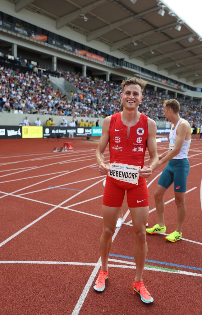Läufer in rotem Einteiler mit Startnummer steht auf roter Bahn vor vollen Tribünen beim Meeting Goldenes Oval Dresden.
