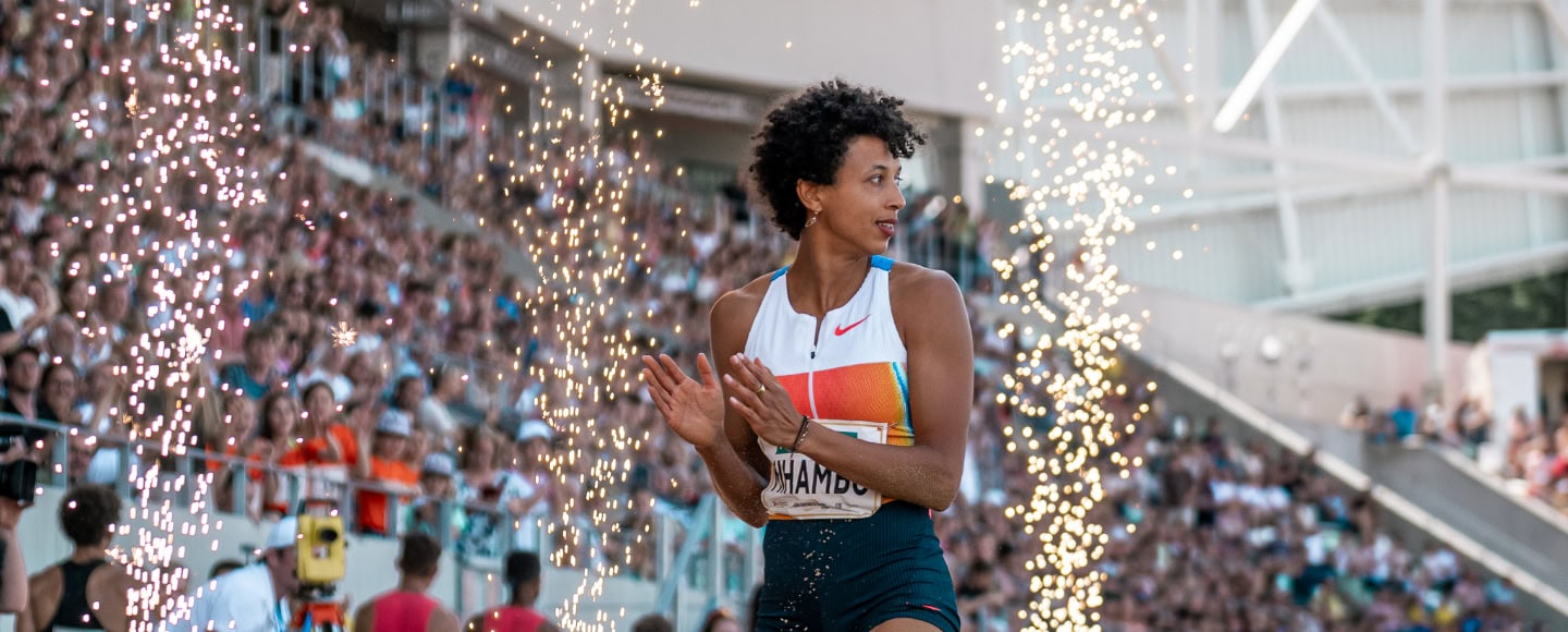 Leichtathletin klatscht zwischen Funkenfontänen vor voll besetzten Rängen beim Meeting Goldenes Oval Dresden im Stadion.
