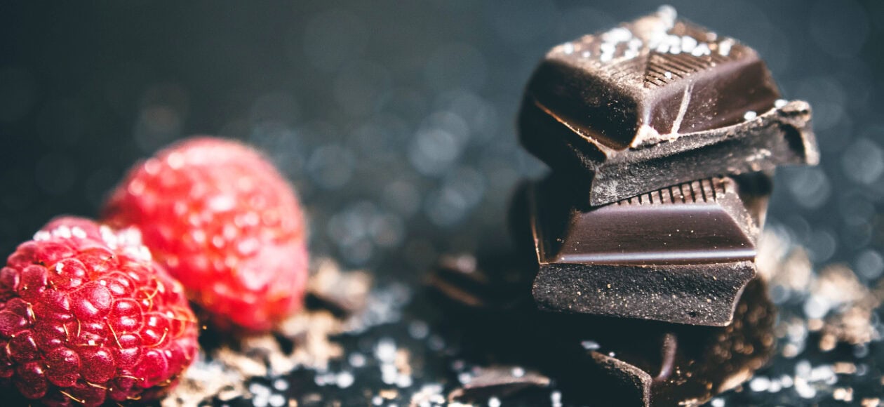 Nahaufnahme von dunkler Schokolade und frischen Himbeeren, ideal für Schokoladenliebhaber in Dresden.