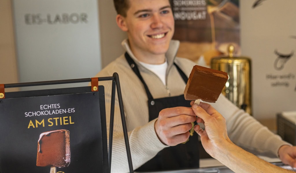 Mann bietet Schokoladen-Eis am Dresdner Stand an.