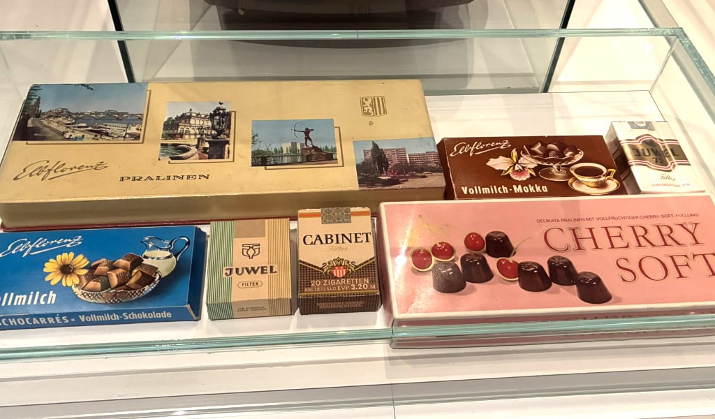 Blick auf eine Glasvitrine mit verschiedenen Schokoladensorten und Pralinen in Dresden, inklusive Marken und Verpackungen.