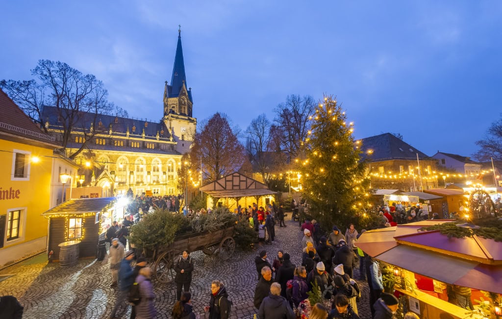 Buden und Bäume mit Lichterketten auf einem PLatz vor einer angeleuchteten Kirche 